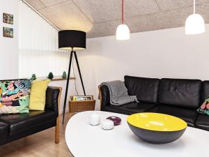 Brovstにある8 person holiday home in Brovstのリビングルーム(黒いソファ、テーブルの上に黄色いボウル付)