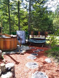 un patio trasero con hamaca, bañera y árboles en Le petit Cottage du Grand Boisé, en Lac-Simon