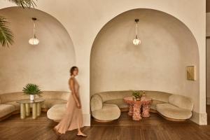 a woman in a pink dress walks in a room with couches at Santa Monica Proper Hotel, a Member of Design Hotels in Los Angeles