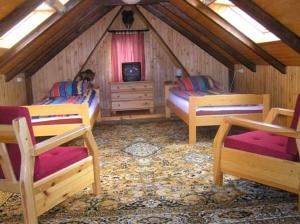 a attic room with two beds and a tv at Domek Myśliwski Wilkasy Zalesie in Wilkasy
