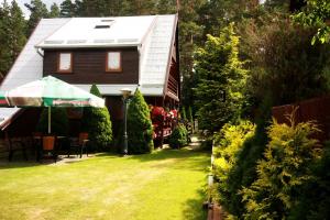 een huis met een tuin met een huis met een groen gazon bij Domek Myśliwski Wilkasy Zalesie in Wilkasy