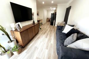 een woonkamer met een blauwe bank en een flatscreen-tv bij The Retreat Terrigal 3bed 100m to beach in Terrigal