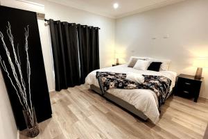a bedroom with a large bed with black curtains at The Retreat Terrigal 3bed 100m to beach in Terrigal
