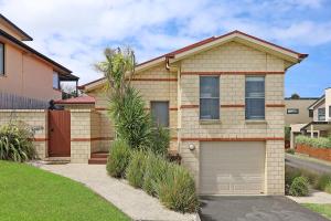 a house with a garage and a palm tree at Hillside - Family Orientated Holiday Home in Warrnambool