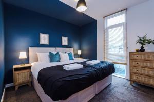 1 dormitorio con 1 cama grande y paredes azules en Rest&Recharge at a Spacious Townhouse by the Etihad (5mins to City Centre, Free Secure Parking) en Mánchester