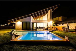 a swimming pool in front of a house at night at Mencey Loco Beach House in São Miguel do Gostoso