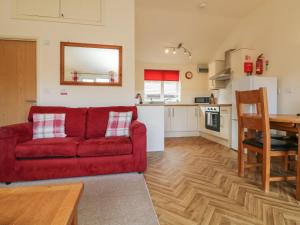 a living room with a red couch and a kitchen at 3 Manleigh Park in Ilfracombe