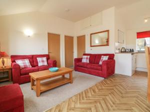 a living room with two red couches and a table at 3 Manleigh Park in Ilfracombe