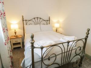 una camera da letto con un letto con lenzuola bianche e due lampade di No 1 The Granary a Llangefni