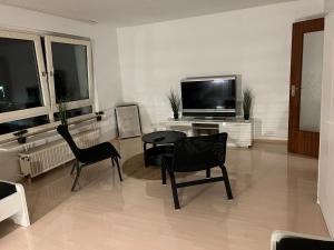蓋爾森基興的住宿－A&V Apartments Sweet Home，客厅配有两把椅子、一张桌子和电视