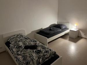 a bedroom with two beds and a night stand with a lamp at A&V Apartments Sweet Home in Gelsenkirchen