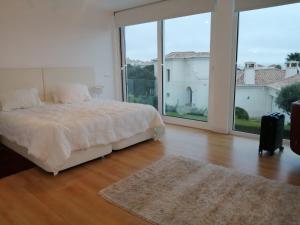 a bedroom with a bed and a large window at White beach luxury vila in Sagres