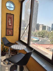 a room with two chairs and a window with a view of a city at Loft Corredor Financiero Reforma in Mexico City