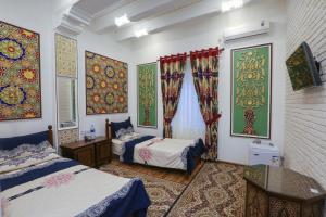 1 Schlafzimmer mit 2 Betten und Gemälden an den Wänden in der Unterkunft Goldenbukhara boutique hotel in Buxoro