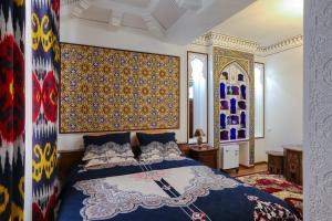 Schlafzimmer mit einem Bett mit blauer Decke in der Unterkunft Goldenbukhara boutique hotel in Buxoro