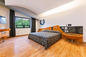 een slaapkamer met een bed, een bad en een televisie bij Hotel Pasadena CDMX in Mexico-Stad