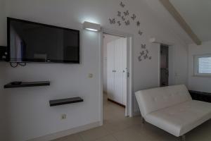 a living room with a white chair and a flat screen tv at Apartments Marco Polo in Rab