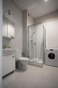 a bathroom with a shower and a toilet and a washing machine at Apartament Fabrykanta by Good Time in Łódź