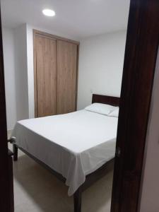 1 dormitorio con cama blanca y armario de madera en Acogedora Casa Circasia, en Circasia