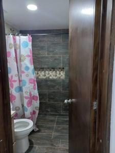 y baño con aseo y cortina de ducha. en Acogedora Casa Circasia, en Circasia