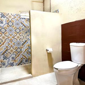 a bathroom with a toilet and a tile wall at Bokatrip El Llano in Oaxaca City