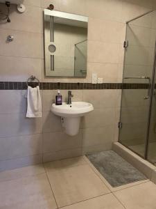 a bathroom with a sink and a shower with a mirror at Green Court Serviced Apartments in Accra