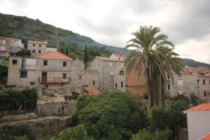 a village with a palm tree and buildings at Rooms by the sea Vis - 3034 in Vis