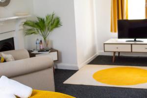 a living room with a couch and a television at SHM Stays Great for long term stays & Short Stays, 15 min drive to City Centre & Airport 2 min walk to Shops and Train Station in Birmingham