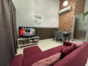 a living room with a purple couch and a tv at CEO2 Soho Business Suite#Netfix#USM #PISA#Airport#Pantai Hospital in Bayan Lepas
