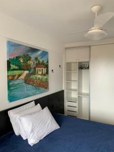 una camera da letto con un letto blu e un dipinto sul muro di Apartamento com Vista do Mar em Residencial com Piscina a Florianópolis Altre 69 foto