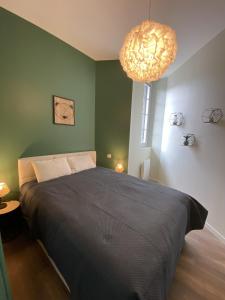 1 dormitorio con cama grande y lámpara de araña grande en Marianne 5, en Bergerac