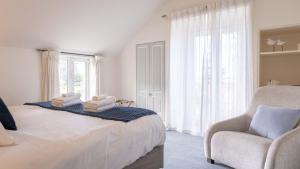 ein Schlafzimmer mit einem Bett, einem Stuhl und einem Fenster in der Unterkunft Sumner Surf Break Apt 1 in Christchurch