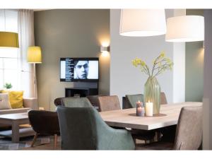 una sala da pranzo con tavolo, sedie e TV di Villa in Zeeland with Outdoor Jacuzzi a Colijnsplaat