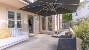a patio with a couch and an umbrella at Sumner Surf Break Apt 1 in Christchurch