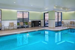 a pool in a hotel room with chairs and tables at SpringHill Suites Edgewood Aberdeen in Bel Air