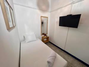 a white room with a bed and a flat screen tv at Hostal Casa Guadalupe in Medellín