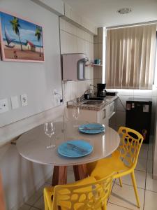 a kitchen with a table and two yellow chairs at Janastí Suítes Praia de Ponta Negra in Natal