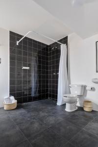 a bathroom with a toilet and a black tiled wall at Posada Independencia in Oaxaca City