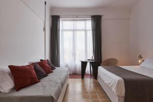 a bedroom with a couch and a window with a table at Posada Independencia in Oaxaca City