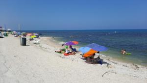 Grupa ludzi siedząca na plaży z parasolami w obiekcie CasaMarina w mieście Marina di Montemarciano
