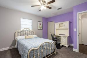 a bedroom with purple walls and a bed and a desk at EntireHouse w/Bush Garden View_Private Heated POOL in Tampa