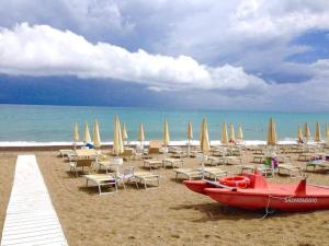 una spiaggia con sedie e una barca rossa sulla sabbia di CASA ZITO a Cirò Marina