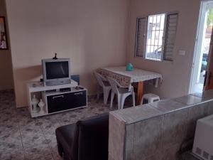 a living room with a tv and a table with chairs at Fala Mansa in Itanhaém