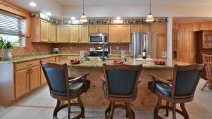 a kitchen with wooden cabinets and a large island with chairs at Seven Springs Woodridge 3 Bedroom Premium Condo, Sleeps 7! condo in Champion