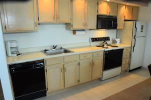een keuken met houten kasten en zwarte apparaten bij Seven Springs Stoneridge 3 Bedroom Standard Condo, Mountain Views! condo in Champion