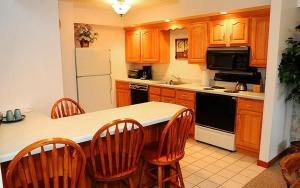 a kitchen with wooden cabinets and a kitchen island with chairs at Seven Springs Deluxe Condo near Pool in Champion