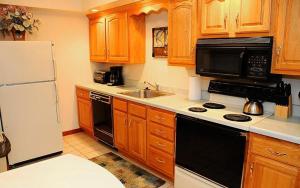 a kitchen with wooden cabinets and a white refrigerator at Seven Springs Deluxe Condo near Pool in Champion
