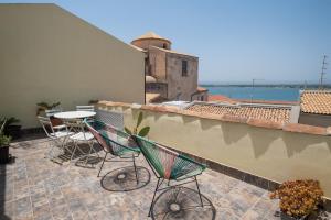eine Terrasse mit 2 Stühlen und einem Tisch auf dem Dach in der Unterkunft Palazzo Gilistro in Syrakus