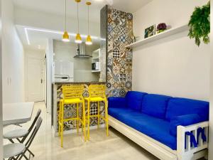 ein Wohnzimmer mit einem blauen Sofa und gelben Stühlen in der Unterkunft M30 - Flat a 3 minutos da praia de Copacabana in Rio de Janeiro