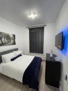 Spacious, Modern 2 Bed Apartment في لندن: غرفة نوم بسرير وتلفزيون بشاشة مسطحة